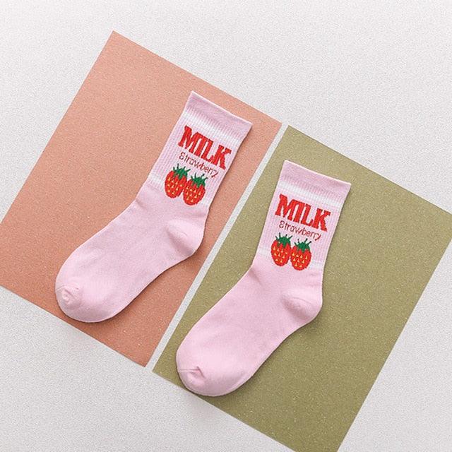 Pair of light pink crew socks with red strawberry graphic and blue “MILK” text