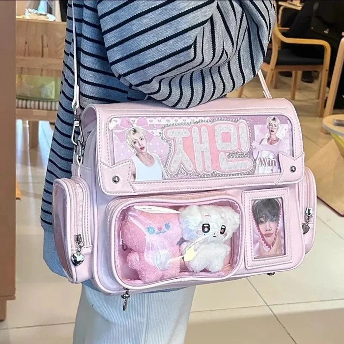 Pink ita shoulder bag with clear front compartments, charm accents, and crossbody strap