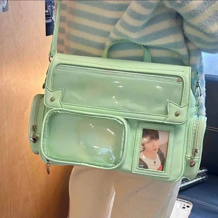 Green ita shoulder bag with glossy finish, clear front panel pocket, and crossbody strap