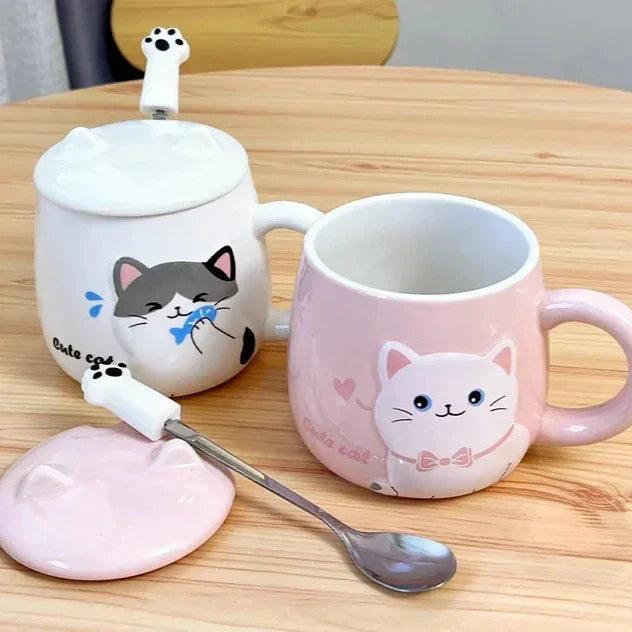 Set of white and pink cat lidded mugs with spoon on tabletop