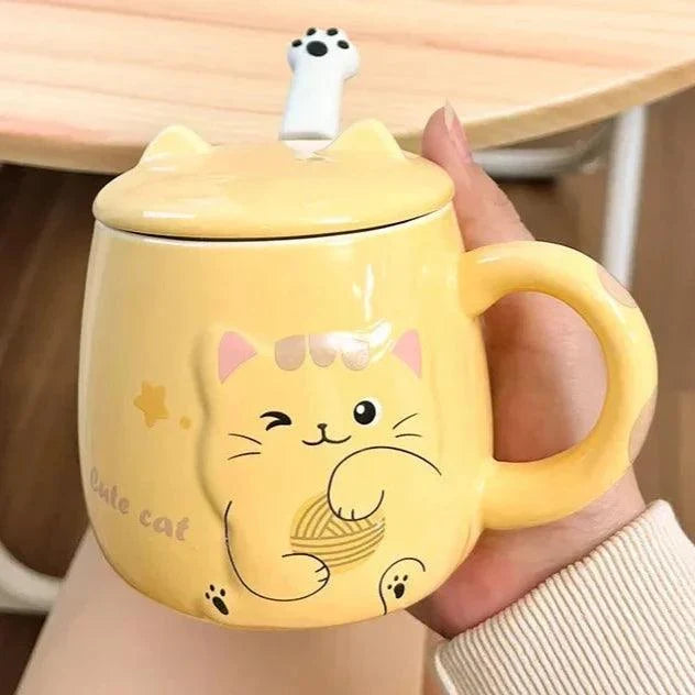Yellow cat face lidded mug held in a hand