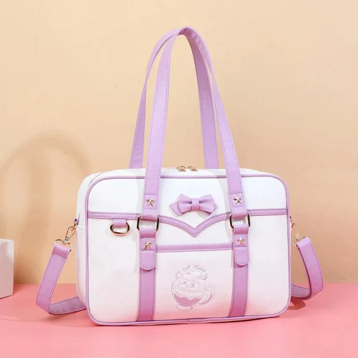 White messenger bag with purple straps, bow front detail, star accents, and shoulder strap