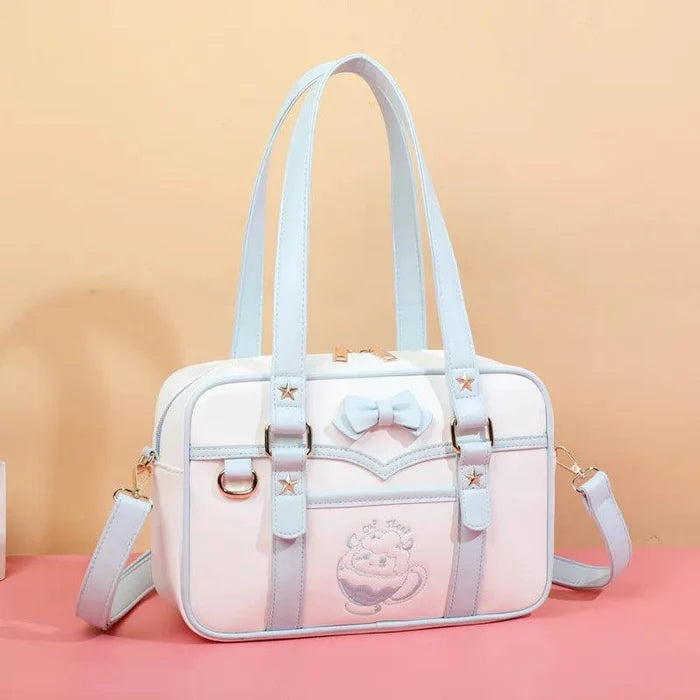 White messenger bag with light-blue straps, bow front detail, star accents, and shoulder strap