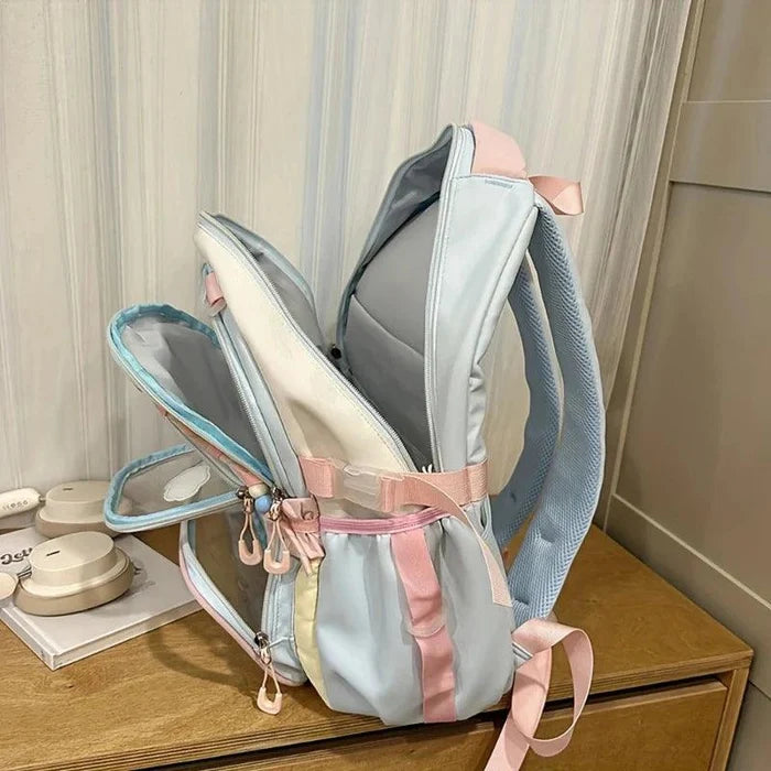 Pastel backpack with gray body, pale blue sides, and pink ribbon-style straps.