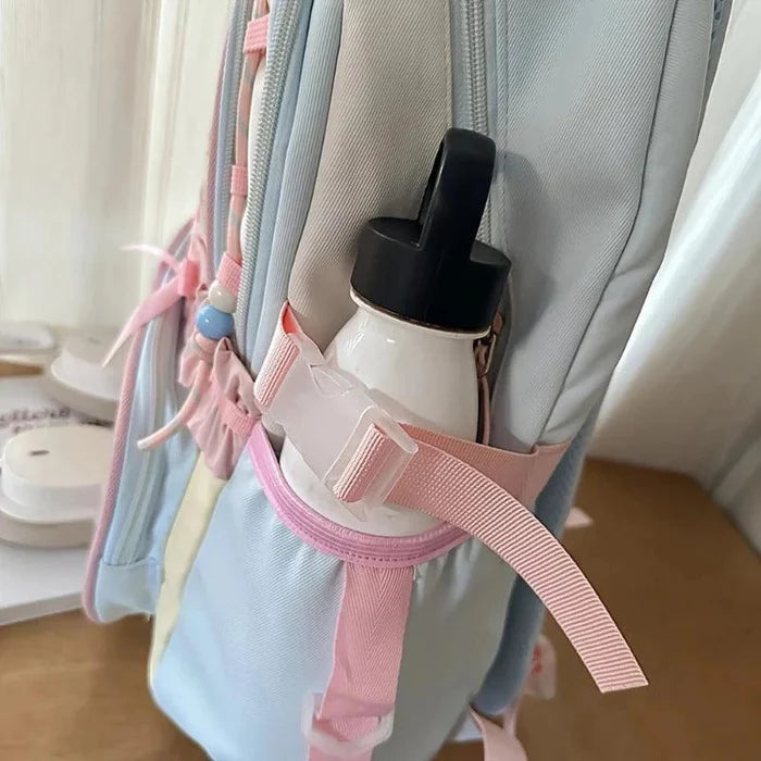 Pastel backpack side pocket with elastic bottle holder and pink-trim strap.