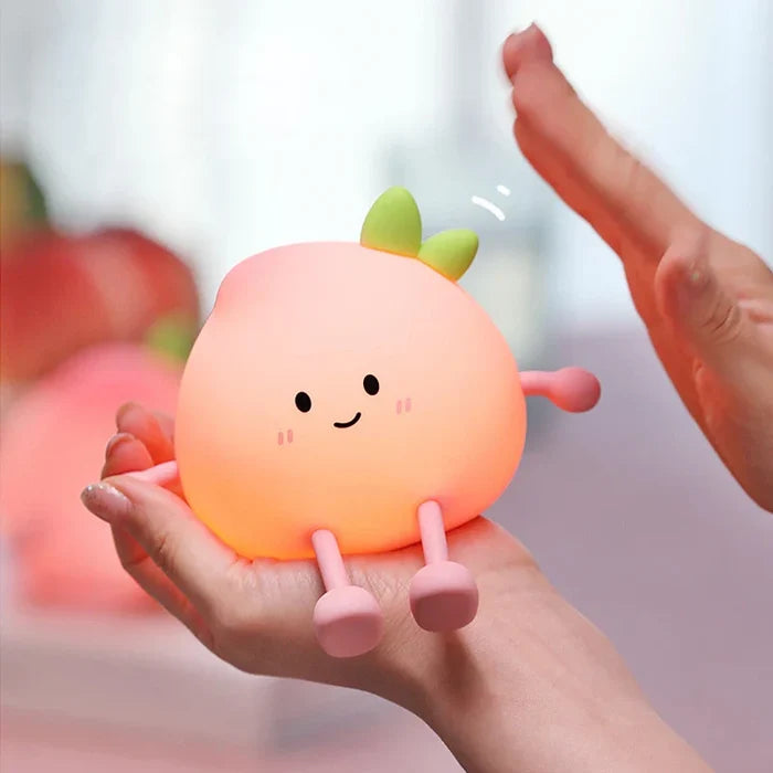 Peach night light with smiling face and green leaves, held in hands, softly lit