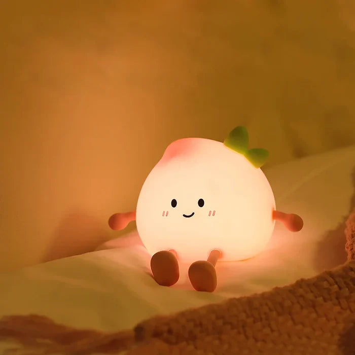 Peach-shaped night light lying down with smiling face and green sprout, glowing softly