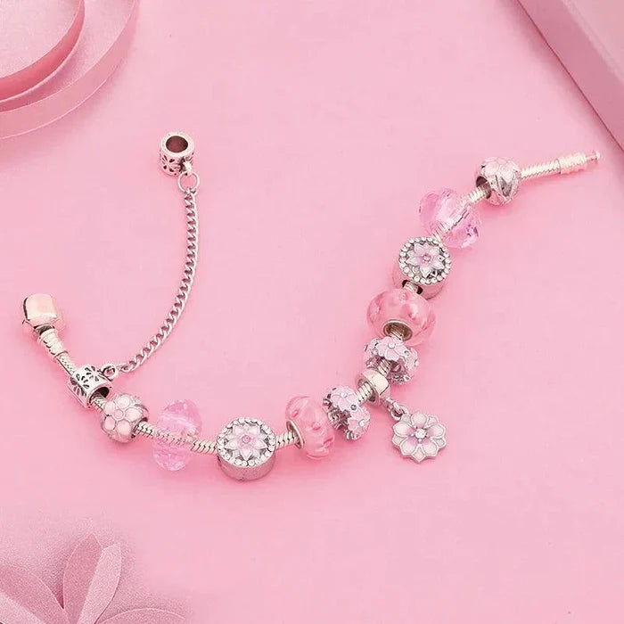 Pink charm bracelet with silver-tone beads and flower charms on a linked chain