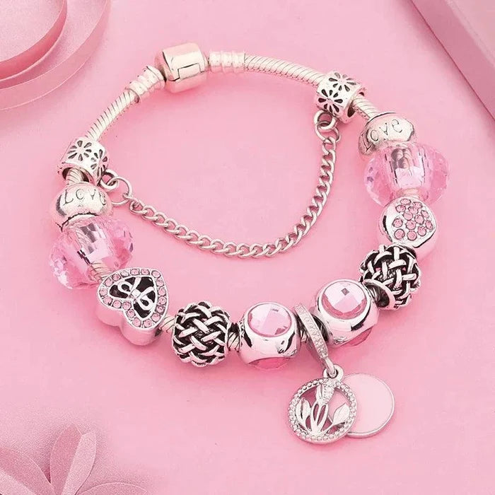 Pink and silver charm bracelet with heart, flower, and bead accents plus dangling tag