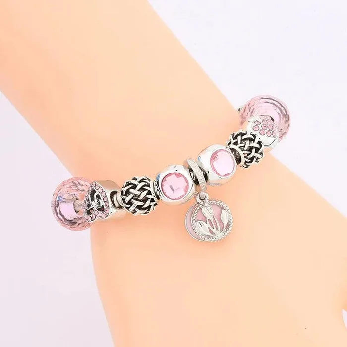 Pink and silver bead charm bracelet with heart and flower charms on a wrist