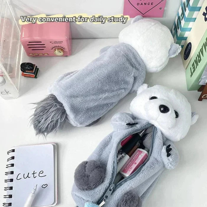 Gray plush otter pencil case with open zipper and pens, plus white-and-blue charm