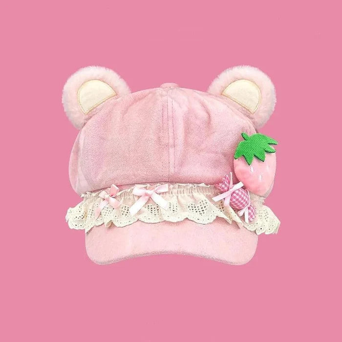 Pink bear-ear cap with front pleats, strawberry appliqué, and scalloped lace trim