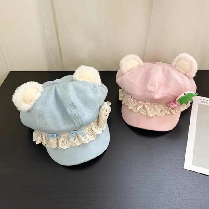Light blue and pink bear-ear caps with scalloped lace trim on display