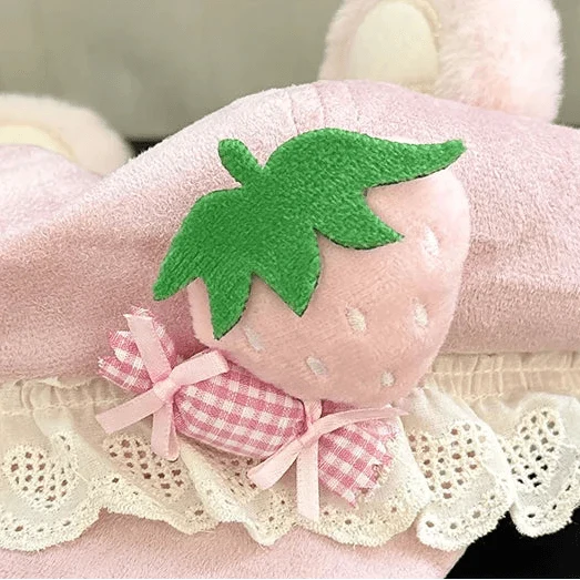 Close-up of pink cap with green strawberry appliqué and white scalloped lace trim