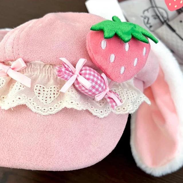 Pink strawberry bunny hat close-up with green strawberry applique, lace trim, and bow