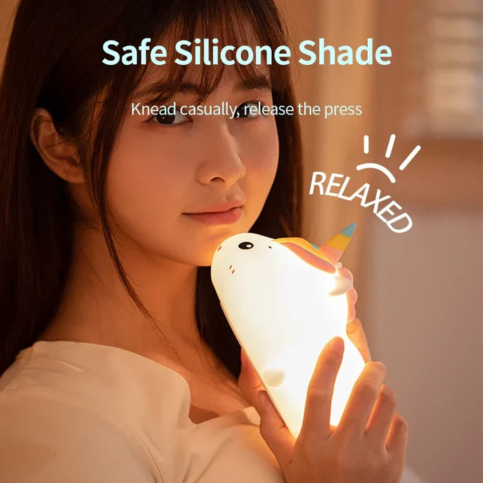 White unicorn night light held by a person, soft warm glow
