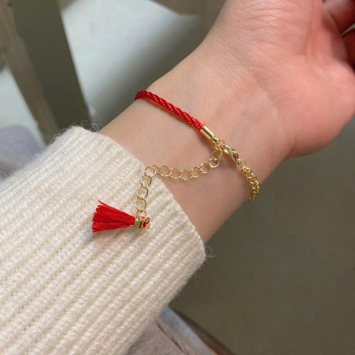 Red cord charm bracelet with gold links, fox head pendant and dangling tassel