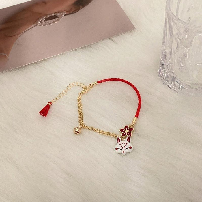 Gold chain fox bracelet with red cord, tassel charm and red flower accents
