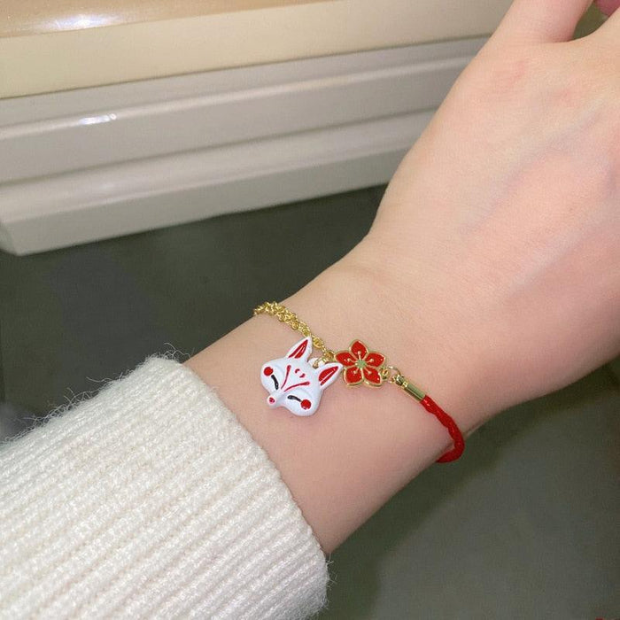 Gold and red fox bracelet worn on wrist with small flower charm and fox face