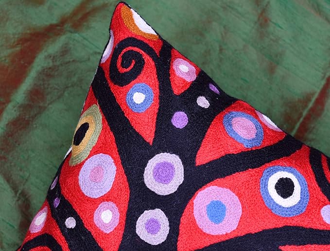 Red and black decorative pillow cover corner with spiral and dot motifs.