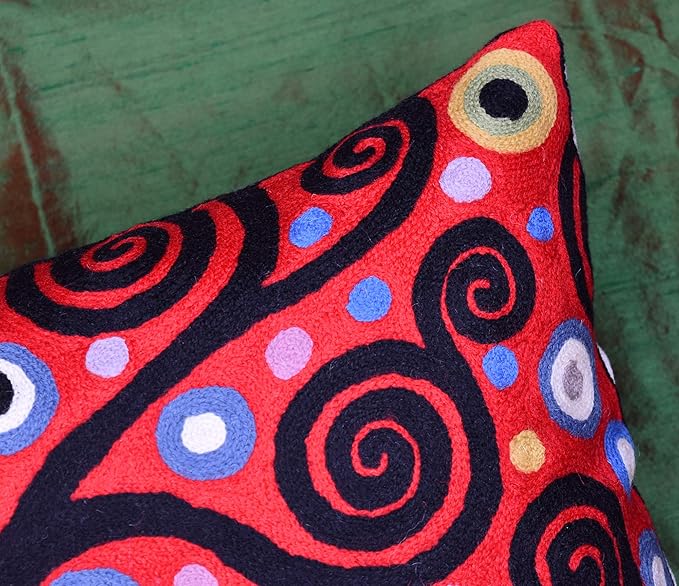 Red decorative pillow cover with large spiral swirls and dotted circles in multicolor.