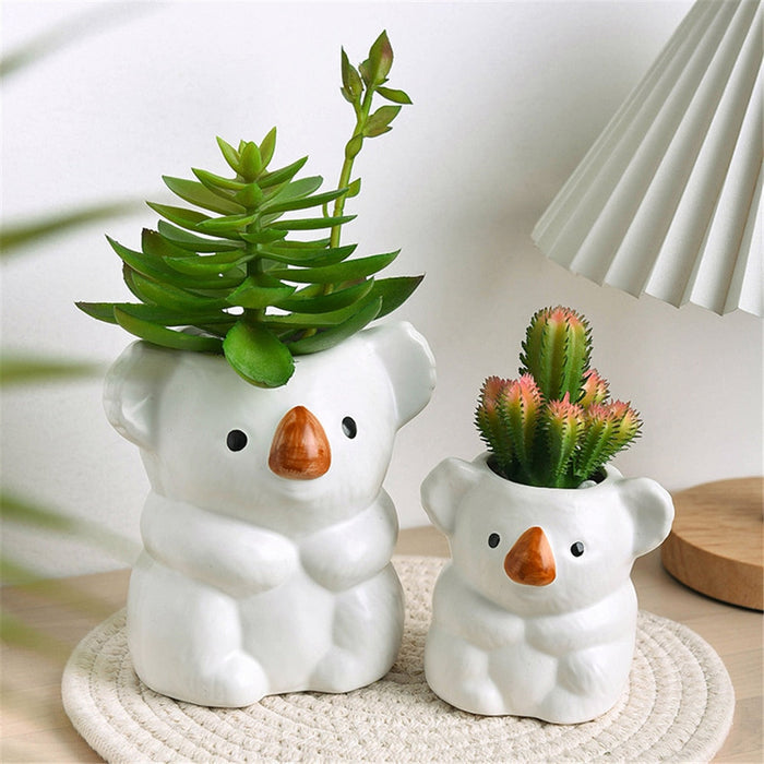 Set of two white koala planter pots with succulents in the heads