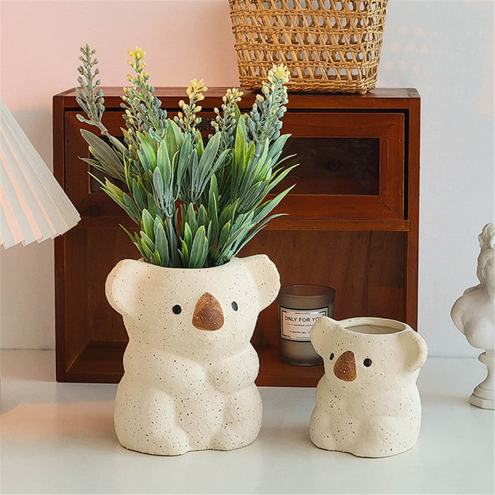 Beige koala planter pot with tall green leaves and a smaller matching pot