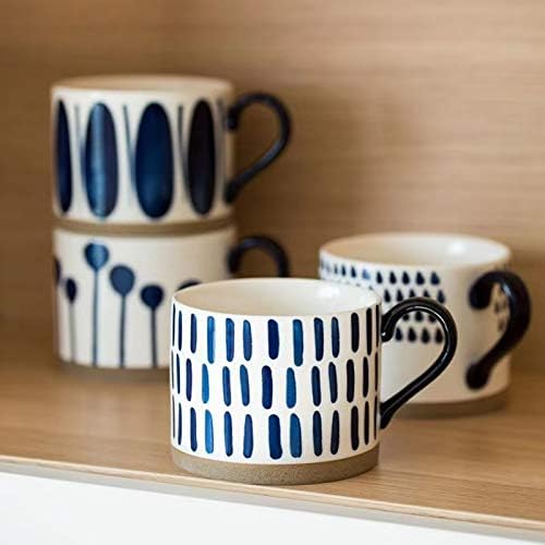 Four navy-and-blue patterned porcelain mugs with black handles, stacked on a shelf
