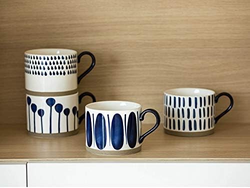 Four white porcelain mugs with navy line and dot patterns and black handles