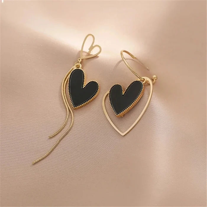 Asymmetric heart dangle earrings with black hearts and gold-tone ear wires and drops.