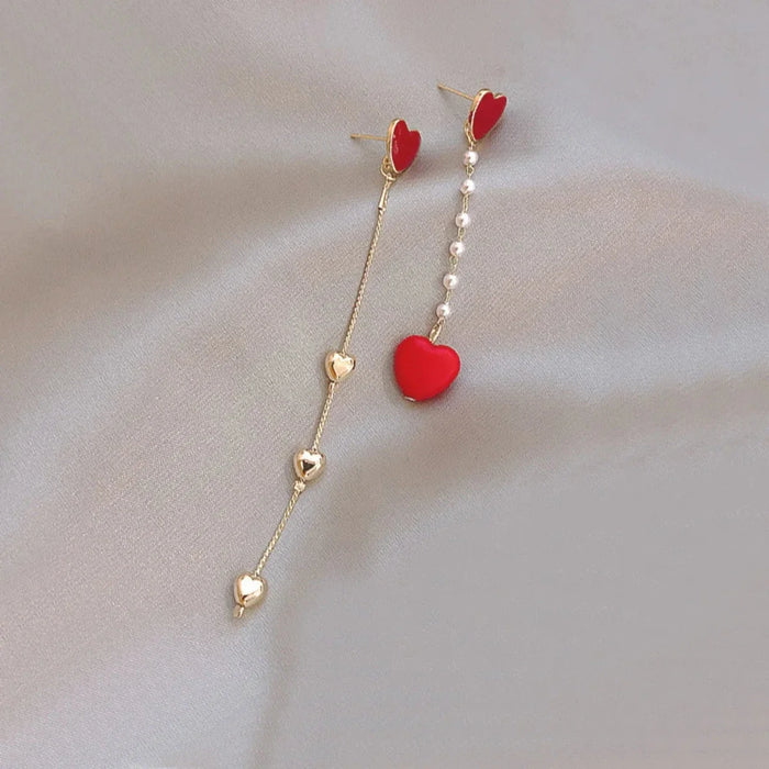 Red heart dangle earrings with long gold chains and small heart drop details.