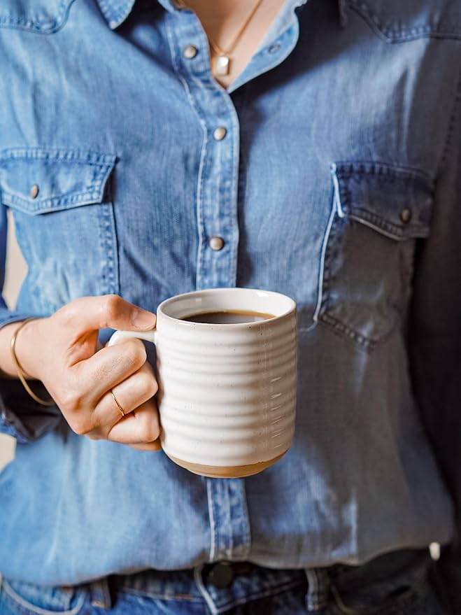 Arctic white ceramic coffee mug with ribbed sides and handle, held by hand