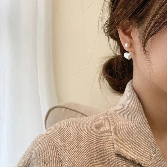 Heart pearl drop earrings with white pearl and heart charm, close on ear