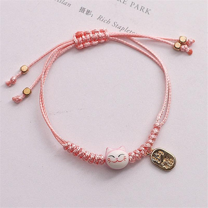 Pink braided cat bracelet with gold coin charm and small bead accents