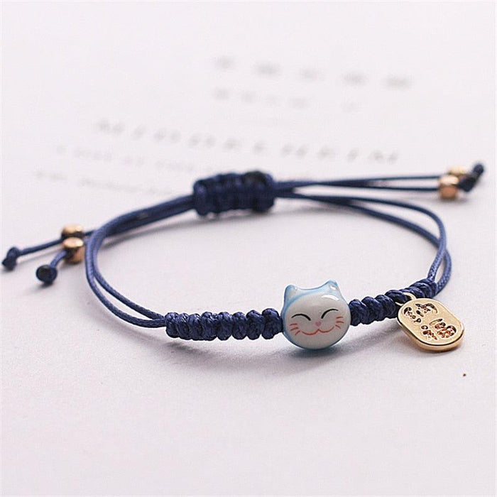 Navy braided bracelet with cat face charm and gold coin tag
