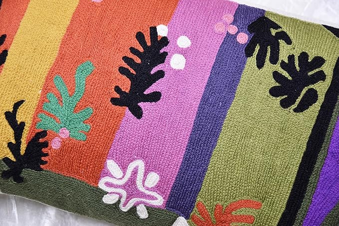 Close-up lumbar pillow cover embroidery with coral, purple, green, and black leaf motifs