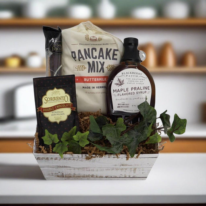 Breakfast gift basket with pancake mix, syrup bottle, chocolate mix packets, and decorative leaves