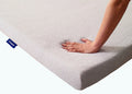 A person's hand presses down to feel the comfort of the Essential Mattress Topper.