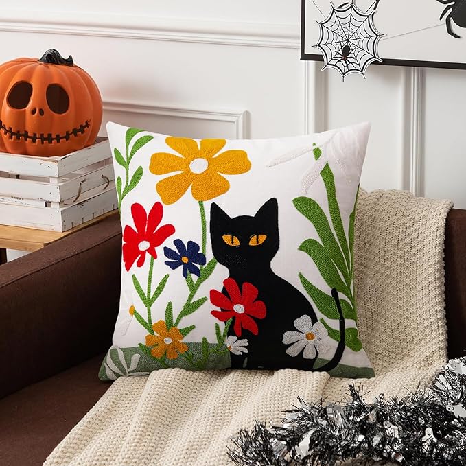 Embroidered pillow cover featuring a black cat and multicolor flowers on white