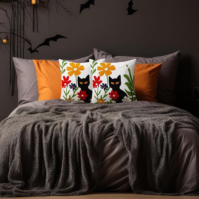 Embroidered pillow cover with black cat and colorful blooms on a white background