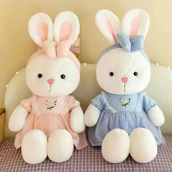 Two bunny plush dolls in pink and blue dresses with embroidered flower details