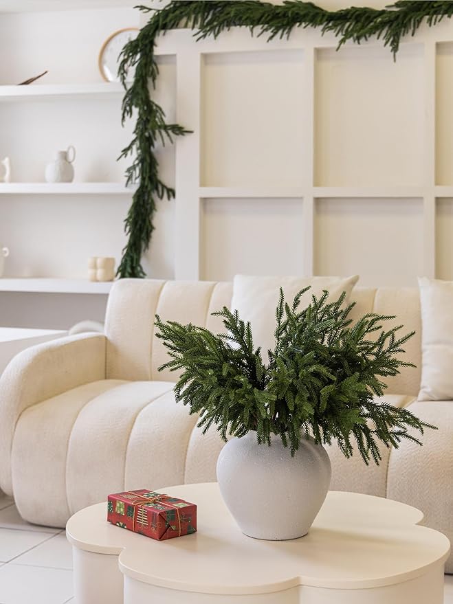 Artificial green pine branch in a white pot, dense evergreen needle tips