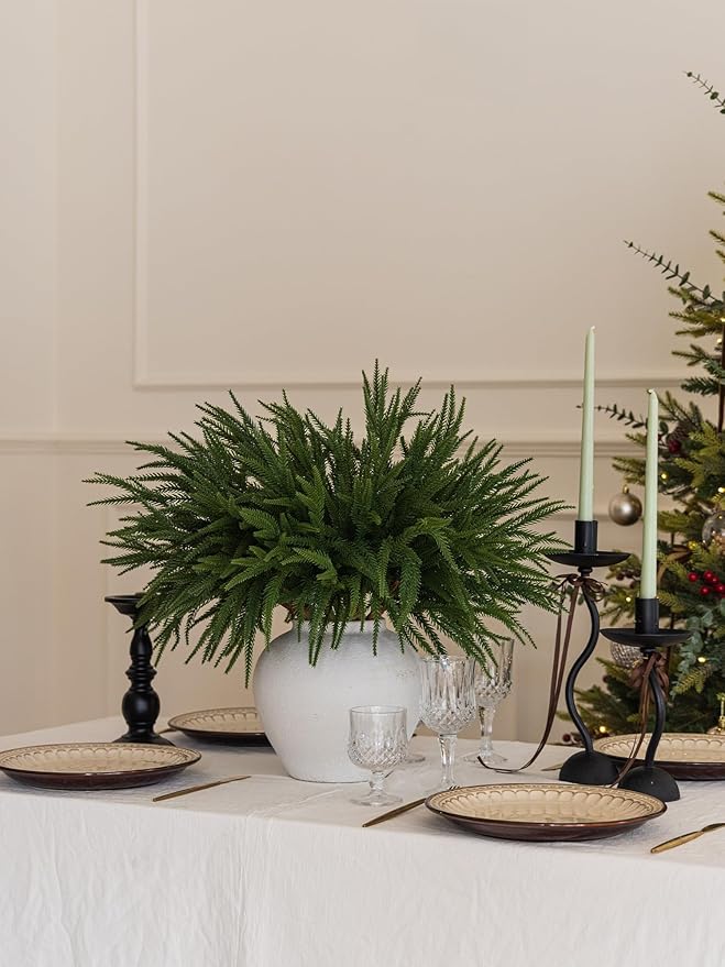 Norfolk pine artificial branch arrangement in a white vase on a dining table