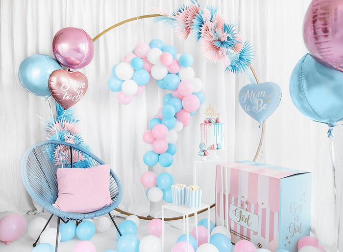 “Mom to Be” heart balloon amid pastel latex balloons and party decorations.