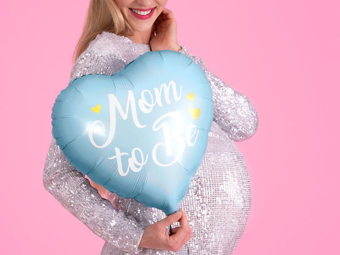 Light blue heart balloon with “Mom to Be” text, held in front of a dress.