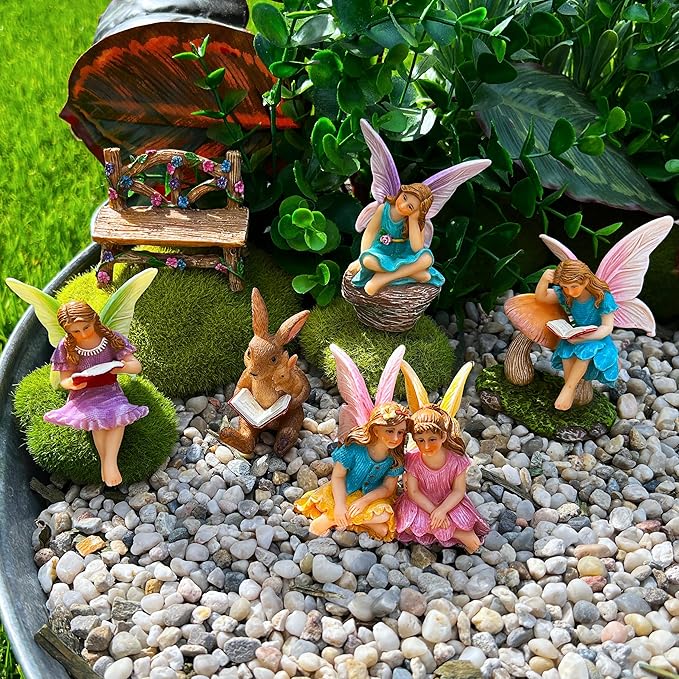 Miniature fairy figurines and bunny reading on gravel tray with small mushroom bench