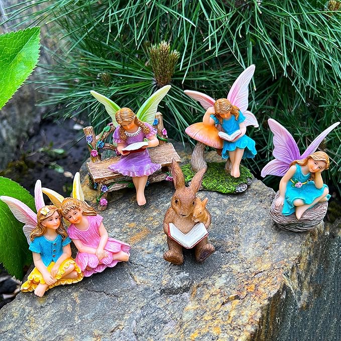 Miniature fairy garden statues on rock with seated fairies and bunny reading an open book