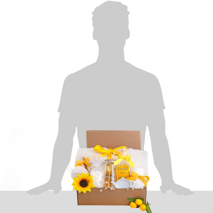 Person holding brown self-care gift box with yellow ribbons, sunflowers, and STASH jars
