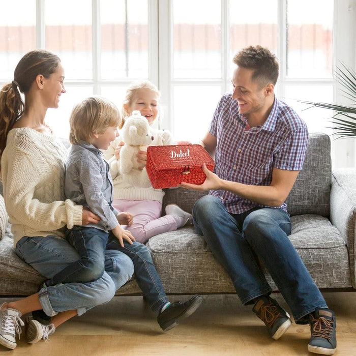 Canasta de mimbre roja con cierre, sostenida por una familia en sofá.