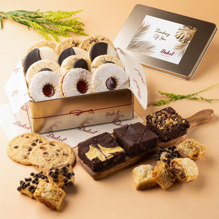 Open gold gift tin of assorted cookies and brownies with lid card showing feather